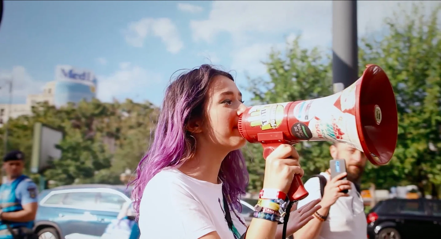 Still from Imaginary Youth showing a young woman speaking through a megaphone